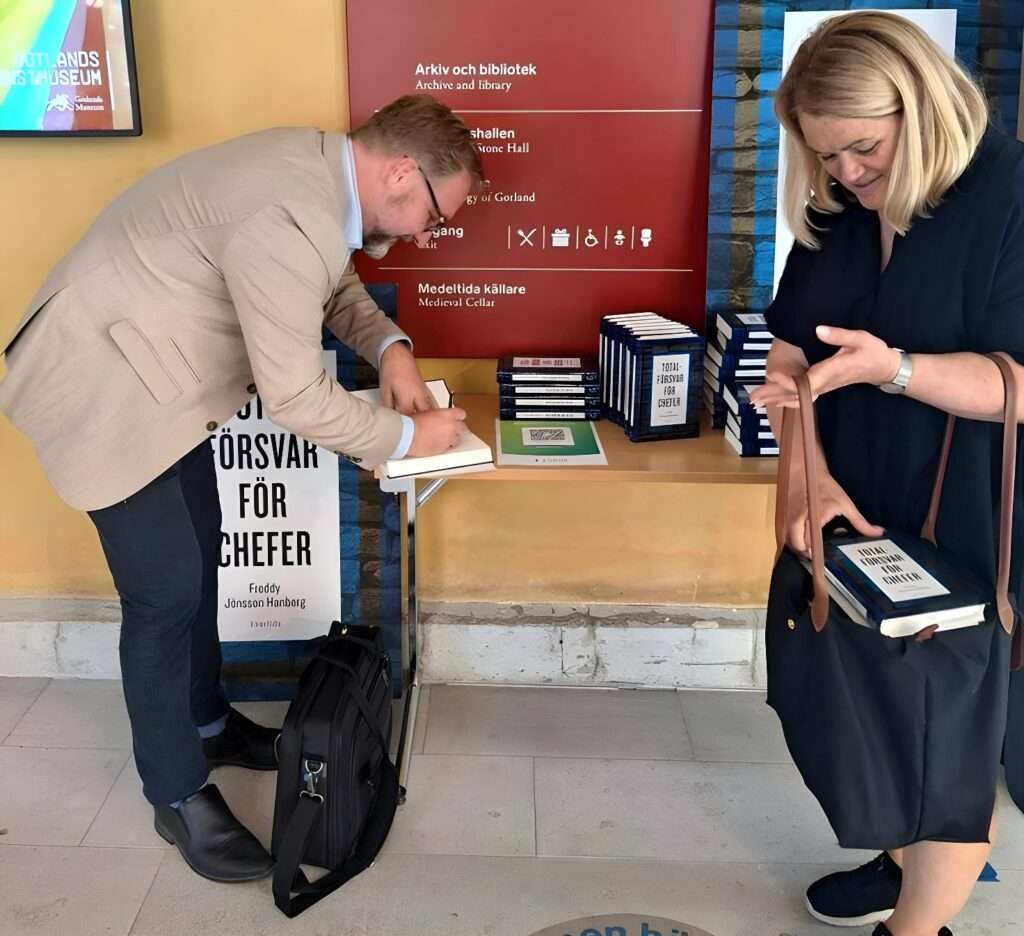 Freddy Jönsson Hanberg signerar böcker och en kvinna har köpt en bok.