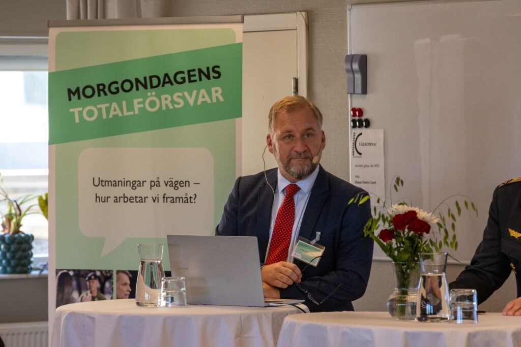 Freddy Jönsson Hanberg sitter framför rollupp för Morgondagens Totalförsvar.